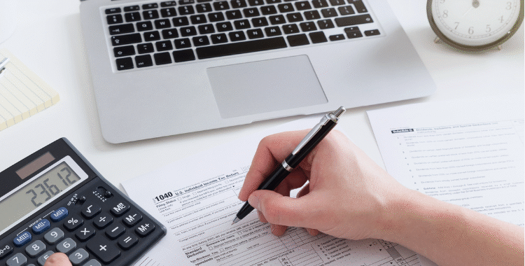 "Person doing online bookkeeping with calculator and laptop, illustrating small business accounting."